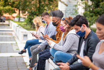 redhead woman student using smart phone covered by face mask during covid19 second wave, new normal lifestyle concept with millennials people looking news on mobile cellphone, selective focus