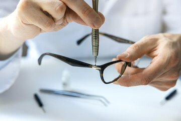 eyewear repair service - optical technician repairing eyeglass frame with screwdriver