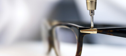 eyewear repair service - screwing the screw in eyeglass frame. copy space - obrazy, fototapety, plakaty