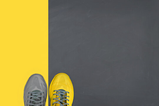 Yellow and grey pair of sneakers on gray-yellow background. Trending colors of 2021. Minimal concept.