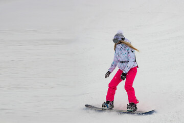 Young blond woman goes snowboarding in the Alpine mountains. Winter sports and recreation.