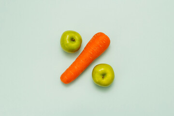 percent sign made from vegetables and fruits. Apple and carrot on a blue background