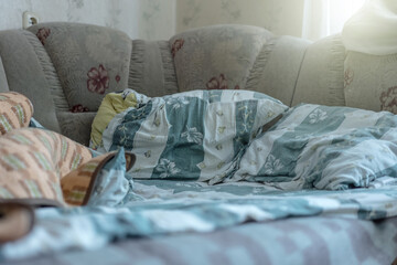 Unmade bed with rumpled linens in bedroom in morning