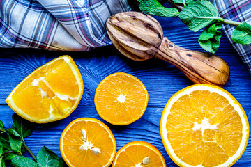 cut oranges with mint leaves and towel on blue kitchen top view