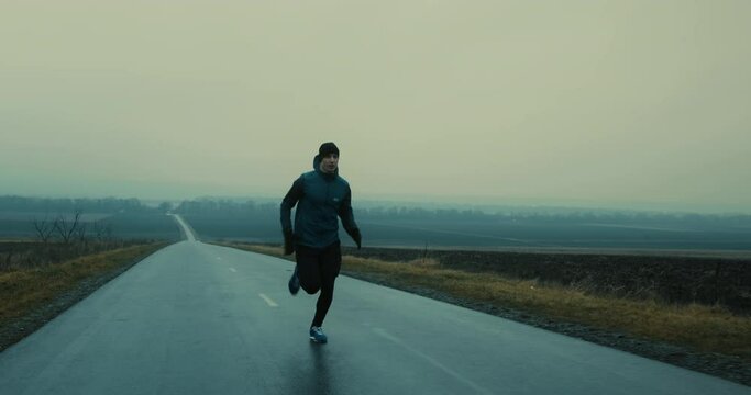 Follow up shot of young athlete man running fast down the empty road getting ready for race competition. Fit man in sportswear jogging early in the morning.