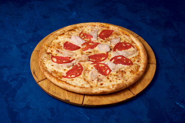 
pizza with tomatoes and chicken meat on a blue background