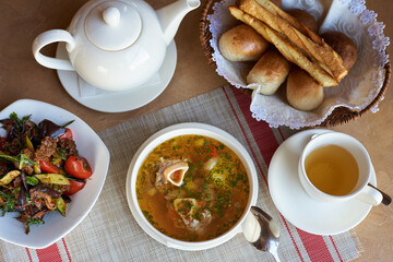 soup with meat on a bone, with salad, bread and tea