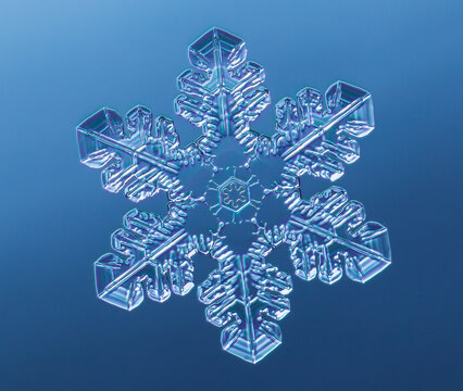 Snowflake on smooth gradient background. Macro photo of real snow crystal on glass surface. This is small snowflake with unusual pattern.