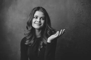 young woman gesturing with her hands on a gray background black and white photography portrait close-up