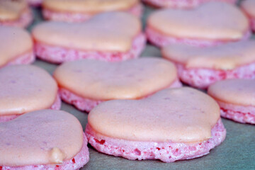 Obraz na płótnie Canvas Pink heart homemade macaron cookies on parchment paper on a baking sheet