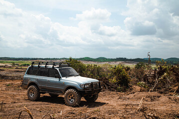 Kuala Lumpur, Malaysia. February, 10, 2021: A jeep, parking on the desert at agriculture farms with cloudy blue sky view