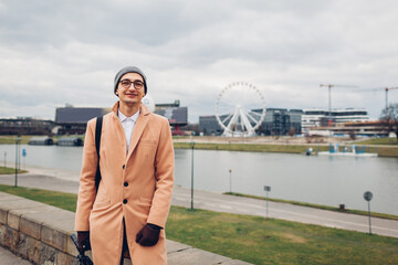 Young man tourist walking along pier by Wisla river in Krakow, Poland enjoying Ferris wheel landscape. Europe trip