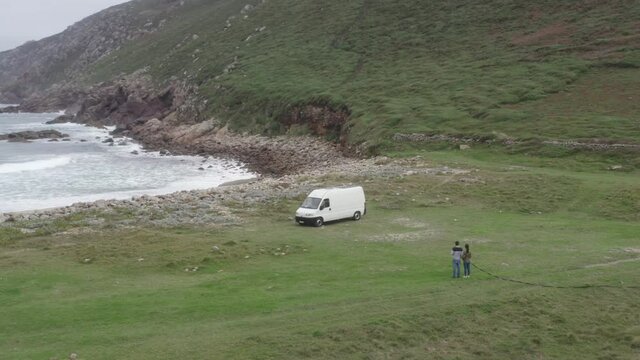 Camper van motorhome view on a sea landscape wild beach with mountains and couple living van life social distancing in Galiza, Spain