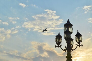 Lanterns against a blue sky with a flying plane.