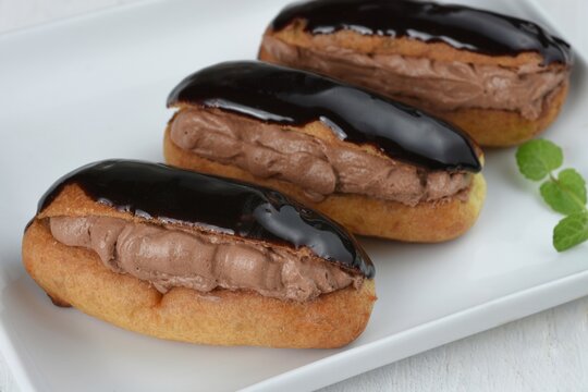Traditional french dessert. Isolated eclair with chocolate cream and chocolate icing on white background. Sweet pastry products