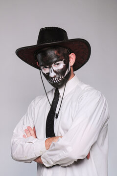 a man in halloween makeup as a dead man with a black skull in a cowboy hat and tie