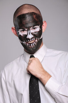 a man in halloween makeup as a dead man with a black skull, bald head and tie