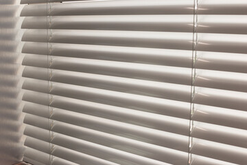 Aluminum blinds. Made from metal. Venetian blinds closeup on the window. Silver color. Closed horizontal blinds in sunny day.
