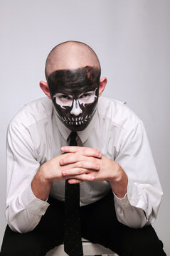 a man in halloween makeup as a dead man with a black skull, bald head and tie