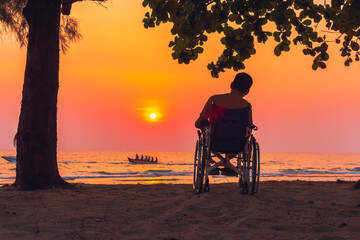 Obraz na płótnie Canvas Asian special child on wheelchair on the sea beach with sunset on travel time in holiday family and learning about nature around the sea,Lifestyle in the education age kids,Happy disabled kid concept.