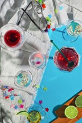 image of liquor glasses after a celebration on crumpled white tablecloth and blue background with remnants of confetti and party glasses, overhead view