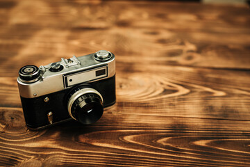 Old retro camera on a charred wooden background. Place for your text.