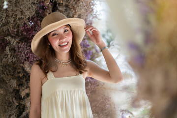  Sweet smiling Asian woman wearing a hat and taking pictures with dried flowers on the back. 