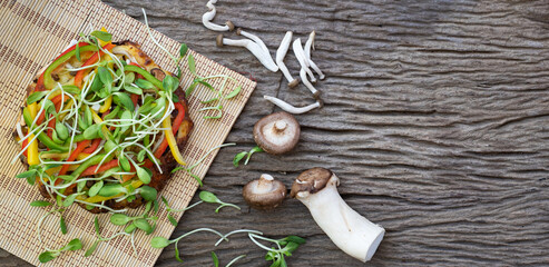Homemade vegetable pizza with sunflower sprout and mushroom a wooden table background