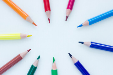 Colorful pencils in a circle pointing to the middle on white background