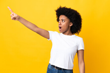 Young African American woman isolated on yellow background pointing away