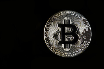 A Bitcoin with black background. Bitcoin is a digital cryptocurrency that can be exchanged for other currencies, products or services.