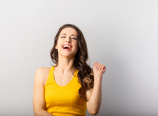 Fototapeta premium Beautiful happy laughing woman with open smiling mouth on blue background with empty copy space. Positive