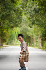 Fototapeta premium A Malay boy in Malay traditional cloth showing his happy reaction during Eid Fitri or Hari Raya celebration.