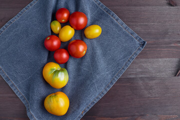 colorful yellow and red ripe tomatoes on a blue kitchen towel. old dark wood background. top view, flat lay