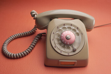Old vintage beige rotary dial telephone isolated on an orange back