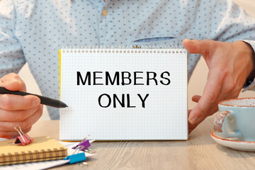 Notebook with text - MEMBERS ONLY - near office supplies.