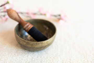 Singing bowl or Tibetan bowl on white blanket with cherry flower.