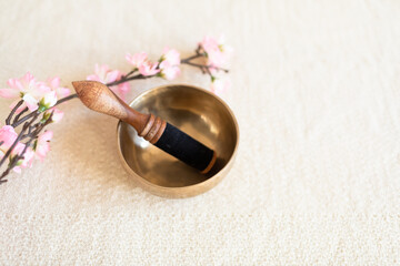 Singing bowl or Tibetan bowl on white blanket with cherry flower.