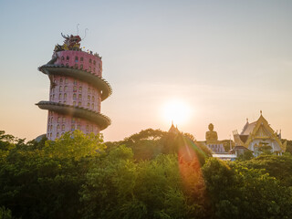 Nakhon Pathom, Thailand, November 14, 2020 : Wat Samphran is notable for its 17-story tall pink cylindrical building with a gigantic red-and-green dragon sculpture curling around the entire height.