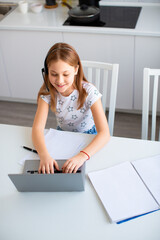 Photo of a pupil girl in front of a laptop monitor during an online school lesson.