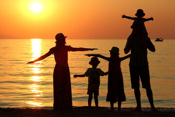 Fototapeta premium family silhouette at sunset by the sea...