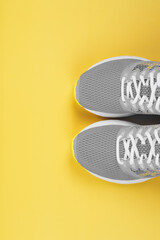 Sports gray sneakers on a yellow background - sport concept, free space.