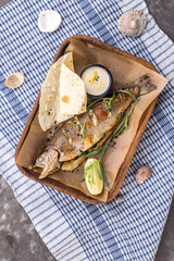 Grilled trout served with white sauce and flatbread on the table