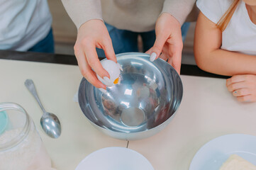 Mom teaches her daughters to cook dough in the kitchen.