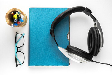 Flat lay table with entertainment, business and education accessories - glasses, earphones and stationeries. white background, top view