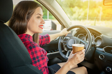 Fototapeta na wymiar Young smiling woman in casual dress with coffee driving modern car
