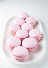 French macaroni cakes on a white oval plate on a light background