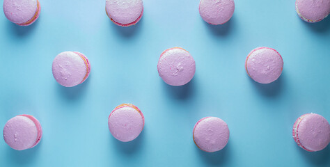 French macaroni cakes in pink on a white oval plate on a blue background.