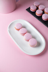 French macaroni cakes in pink on a white oval plate, space for text
