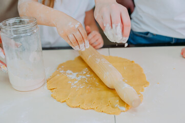 Mom teaches her daughters to cook dough in the kitchen.
